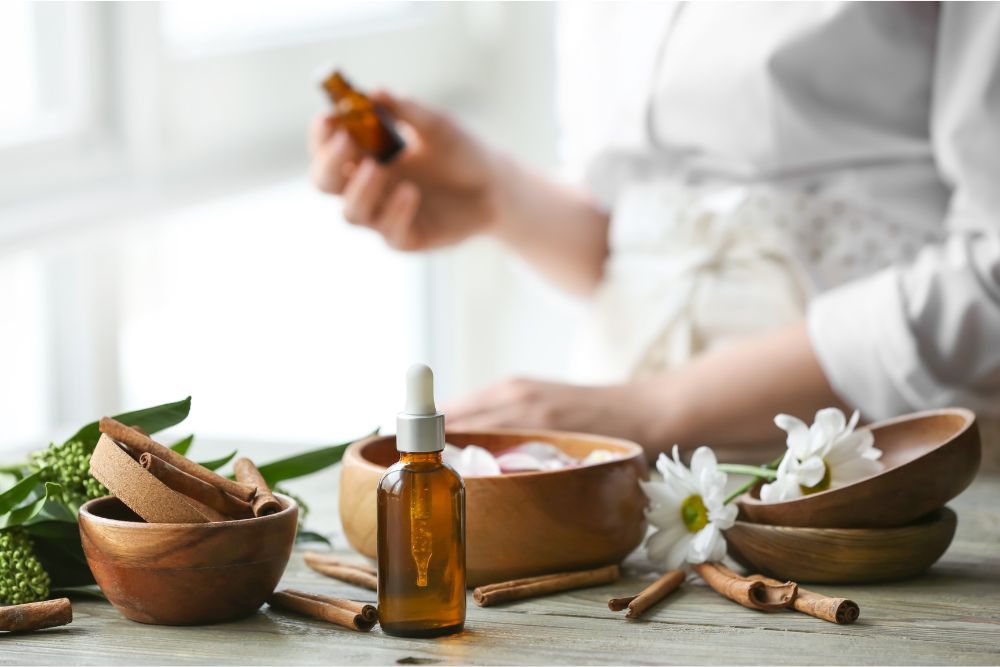 Glasflaskor med eteriska oljor omgivna av färska örter och blommor