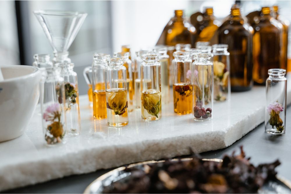 Glasflaskor med olika eteriska örtoljor och färska örter på träunderlag – naturlig aromaterapi