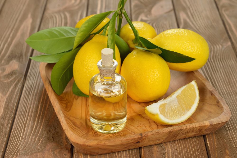 Citronolja i en liten flaska med färska citroner på ett träunderlag