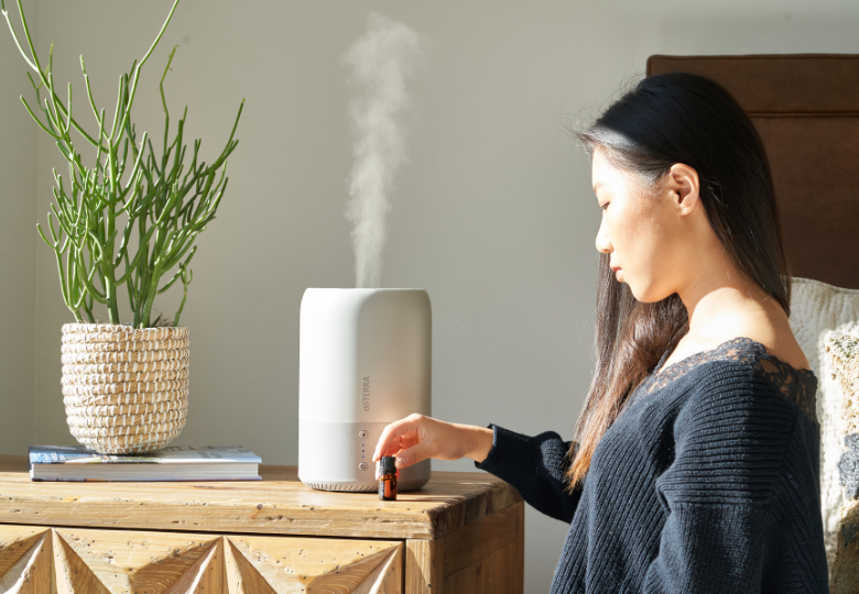 Kvinna som droppar eterisk olja i en aromadiffusor som en del av kvällsförberedelserna.